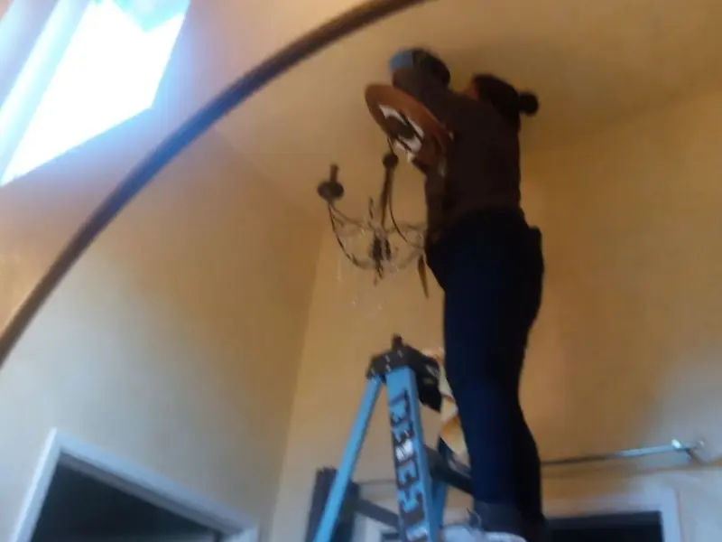Electrician installing a chandelier in a Upper residence